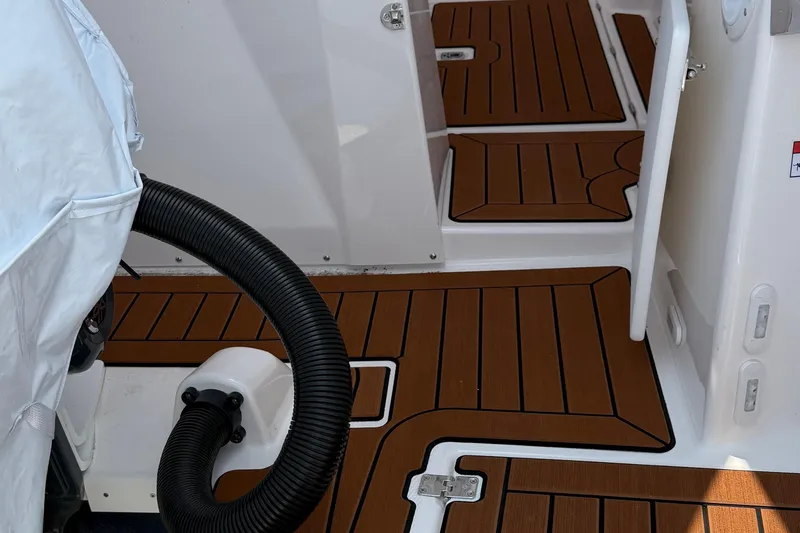 Slide: The Image of 2025 Ranger Tugs R-25 boat interior with wood-patterned flooring and covered equipment. - 4