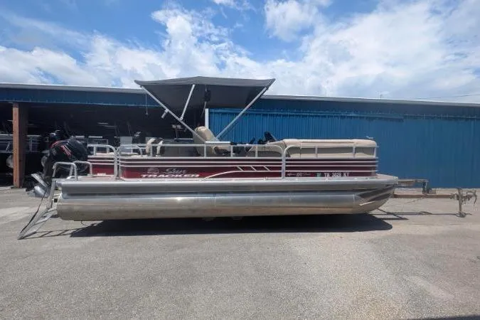 The Image of 2022 Sun Tracker SportFish 22 DLX pontoon boat parked outdoors under a blue sky. - 0