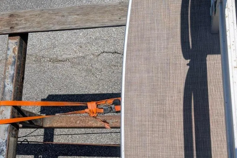 Slide: The Image of 2022 Sun Tracker SportFish 22 DLX boat secured with orange straps on a trailer. - 9