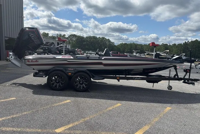 Slide: The Image of 2026 Bass Cat Jaguar STS boat on trailer, parked outdoors under cloudy sky. - 13
