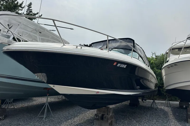 The Image of 2005 Sea Ray 290 SLX boat on stands, black hull, parked outdoors. - 1