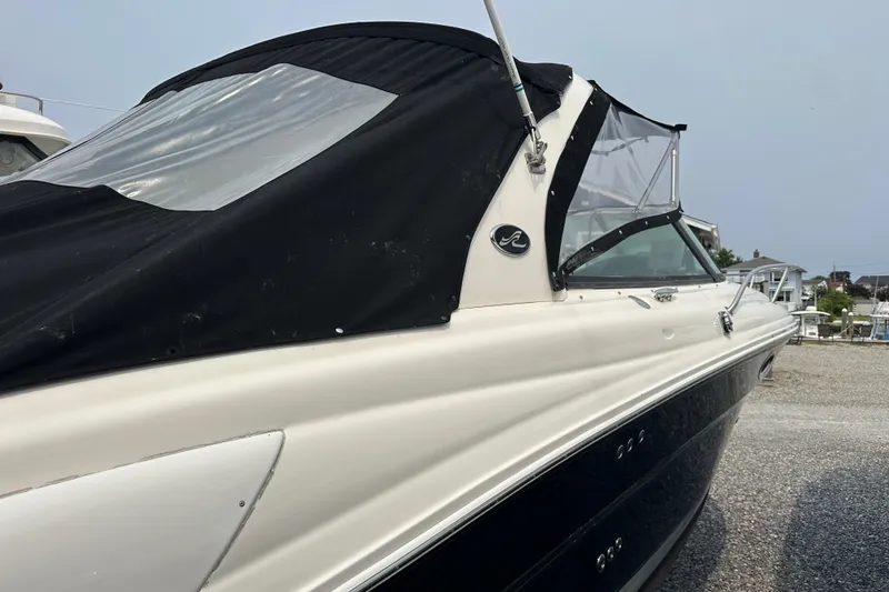 Slide: The Image of 2005 Sea Ray 290 SLX boat with black canopy, parked on gravel. - 3