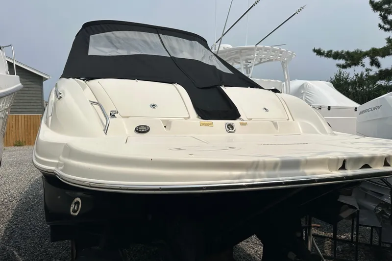 Slide: The Image of 2005 Sea Ray 290 SLX boat with black cover, parked on gravel. - 4