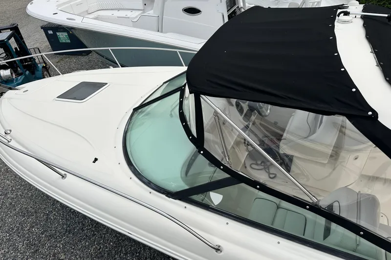 Slide: The Image of 2005 Sea Ray 290 SLX boat with black canopy, docked alongside another vessel. - 5