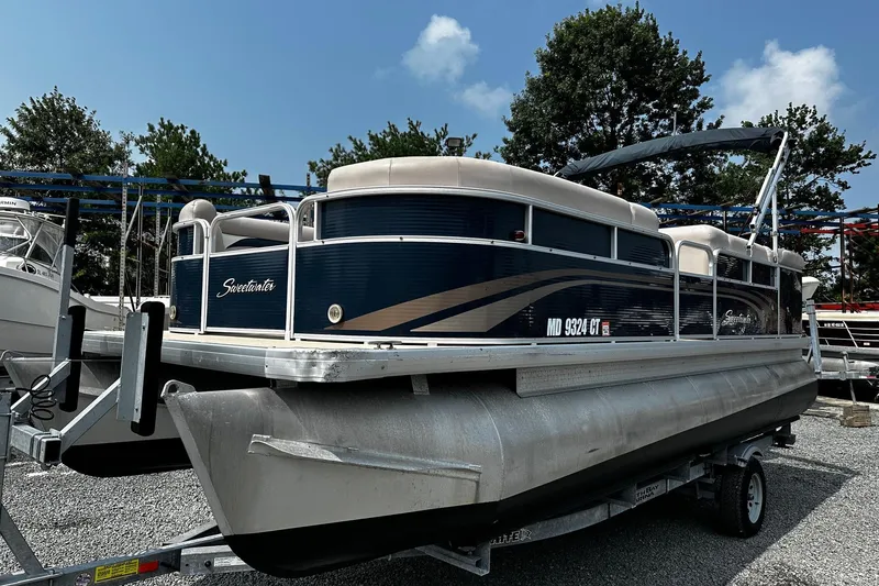 The Image of 2014 Godfrey Sweetwater 2286 Pontoon boat on trailer, parked outdoors under blue sky. - 0