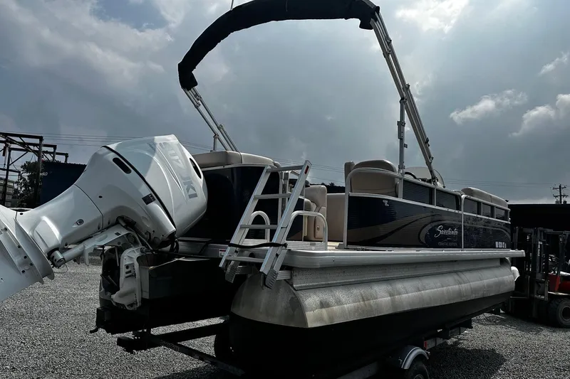 Slide: The Image of 2014 Godfrey Sweetwater 2286 Pontoon boat with Suzuki outboard motor, parked on gravel. - 2