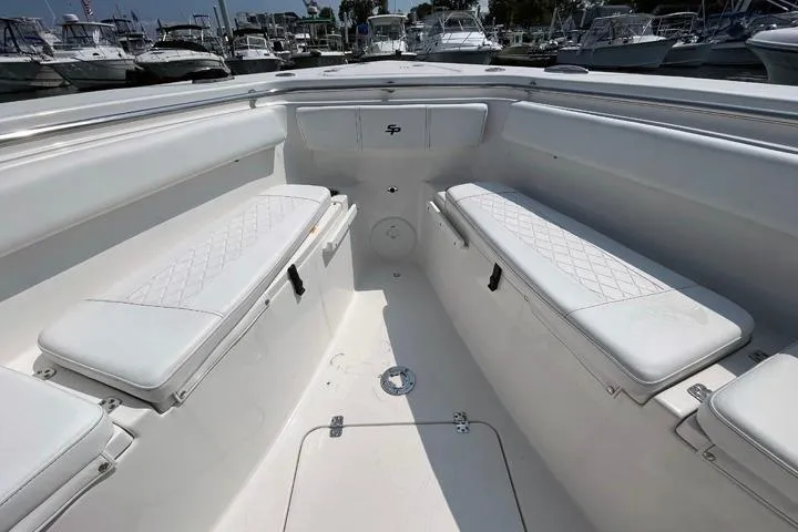 Slide: The Image of 2024 Sea Pro 262 DXL boat interior with white cushioned seating and storage compartments. - 14