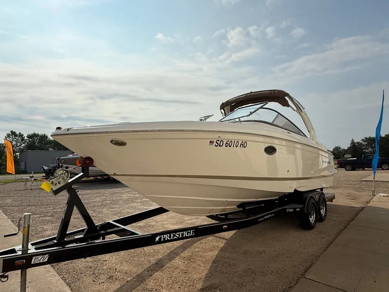 Slide: The Image of 2012 Regal 2700 Bowrider boat on trailer, parked outdoors under a cloudy sky. - 2
