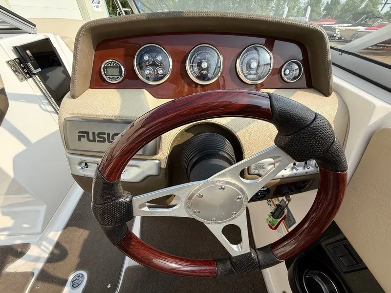 Slide: The Image of Steering wheel and dashboard of 2012 Regal 2700 Bowrider boat, featuring wood accents and gauges. - 20