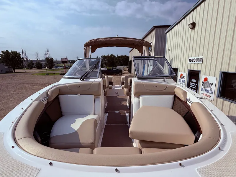 Slide: The Image of 2012 Regal 2700 Bowrider boat with beige seating, parked near a building. - 3