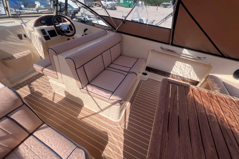 Slide: The Image of 2018 Rossiter 23 boat interior with beige seating, wooden table, and steering wheel. - 12