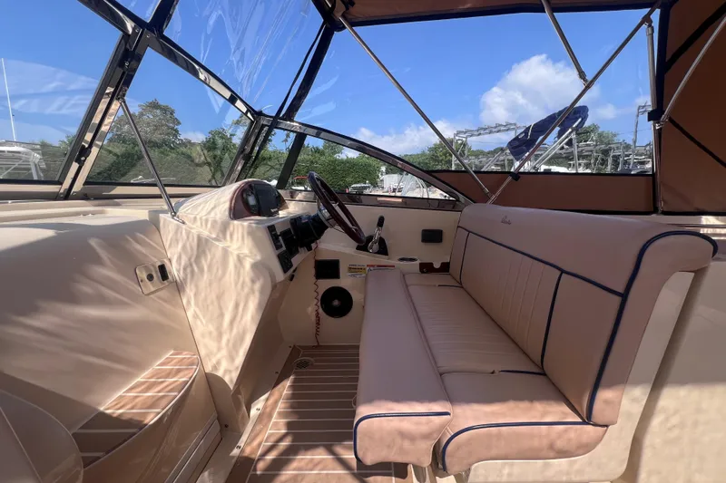 Slide: The Image of 2018 Rossiter 23 boat interior with beige seating and steering wheel under clear blue sky. - 17