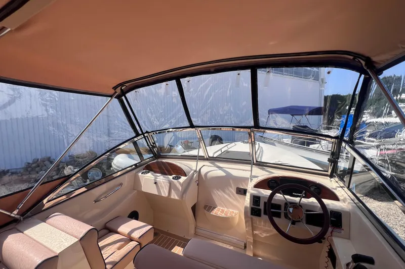 Slide: The Image of 2018 Rossiter 23 boat interior with steering wheel and seating under canopy. - 18