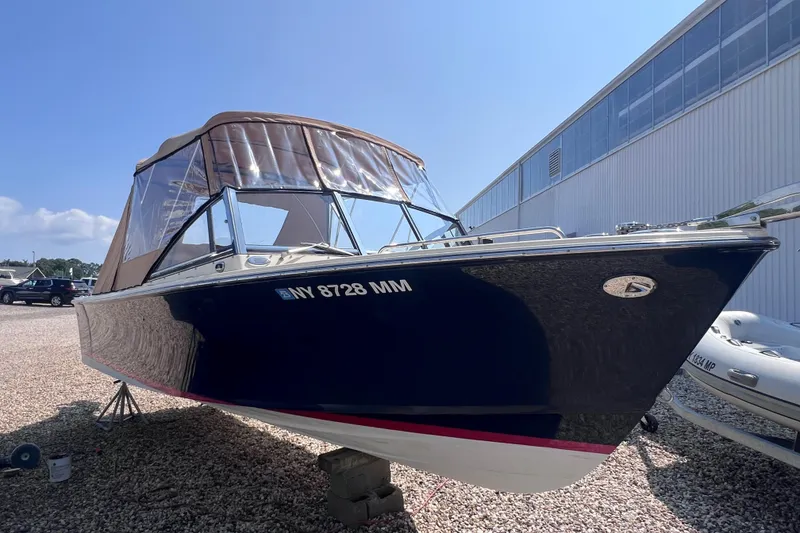 Slide: The Image of 2018 Rossiter 23 boat with canopy, parked on gravel near a building. - 31