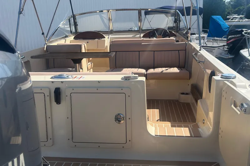 Slide: The Image of 2018 Rossiter 23 boat interior with seating and steering wheel, docked at marina. - 7