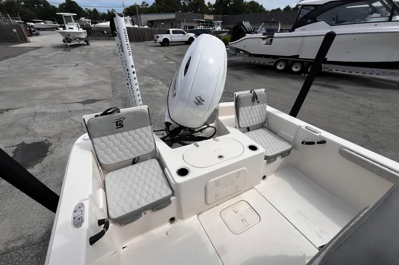 Slide: The Image of 2024 Carolina Skiff 21 LS boat interior with seating and motor, displayed outdoors. - 5