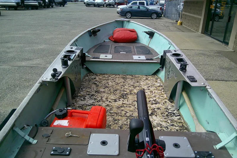 Slide: The Image of 1965 Lund V14 boat interior with fishing gear and equipment, parked in a lot. - 7