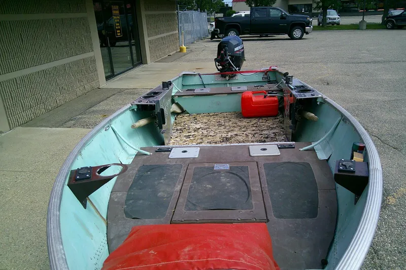 Slide: The Image of 1965 Lund V14 boat with motor and fuel tank, parked outside a building. - 8