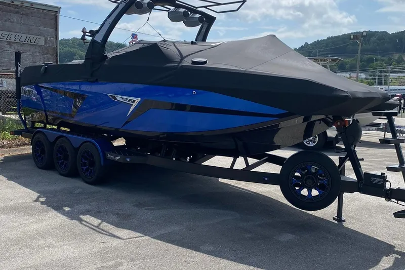 Slide: The Image of 2023 Tigé 24RZX boat in blue on a trailer, covered and parked outdoors. - 19