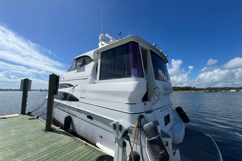 Slide: The Image of 2000 Carver 506 Motor Yacht docked by a scenic waterfront under a cloudy sky. - 53