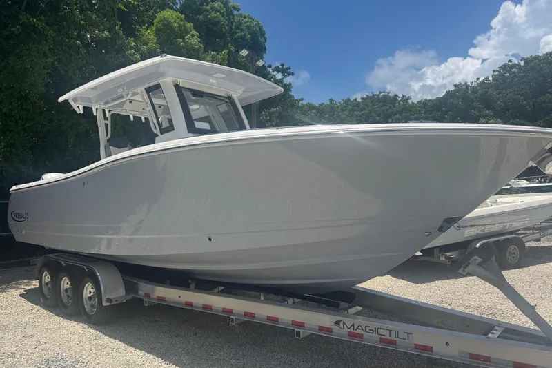 The Image of 2025 Robalo R300 Center Console boat on trailer, parked outdoors under clear sky. - 0