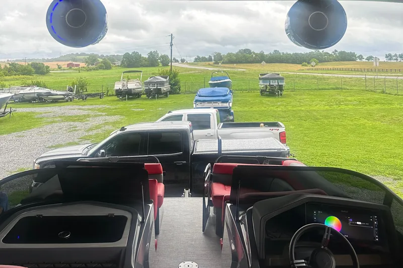 Slide: The Image of 2025 Trifecta Sport RF9 DC boat interior with parked trucks and boats in a grassy area. - 12