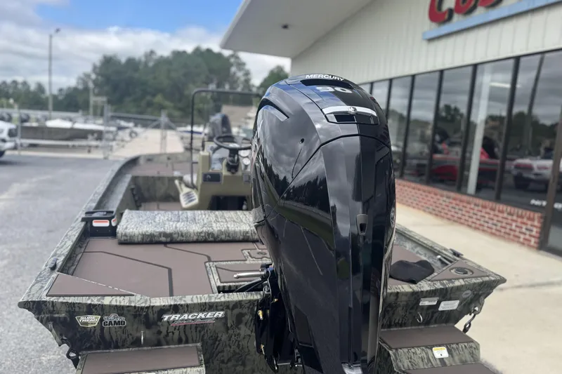 Slide: The Image of 2026 Tracker Grizzly 1860 CC boat with Mercury engine, parked outside dealership. - 2