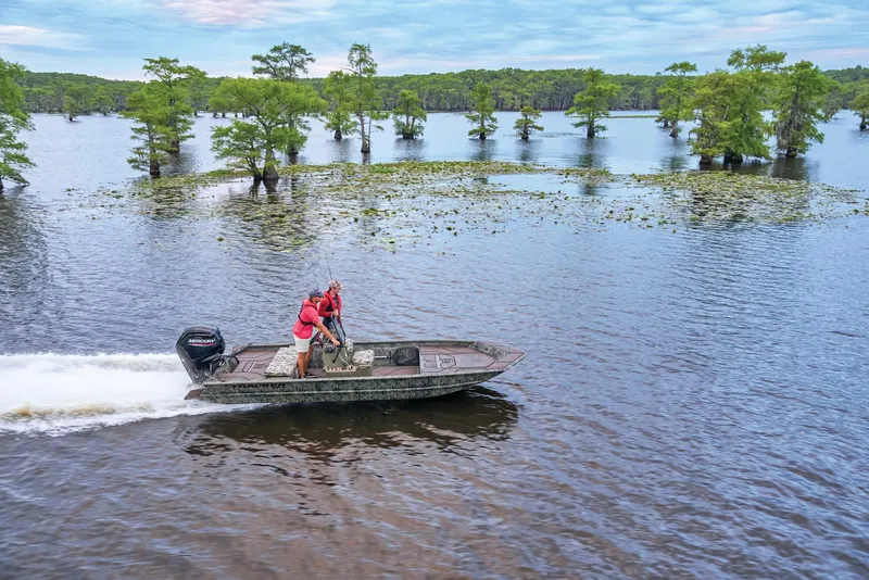 Slide: The Image of Manufacturer Provided Image: 2026 Tracker Grizzly 1860 CC boat cruising on a scenic lake with trees. - 29