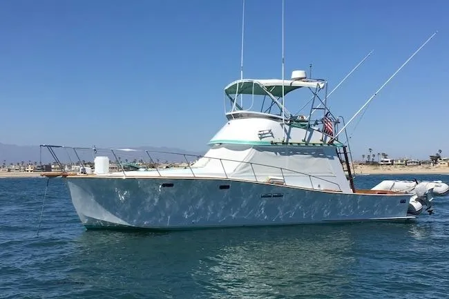 The Image of 1979 Pacific Bluefin Sportfisher boat on calm water, clear sky, coastal background. - 0