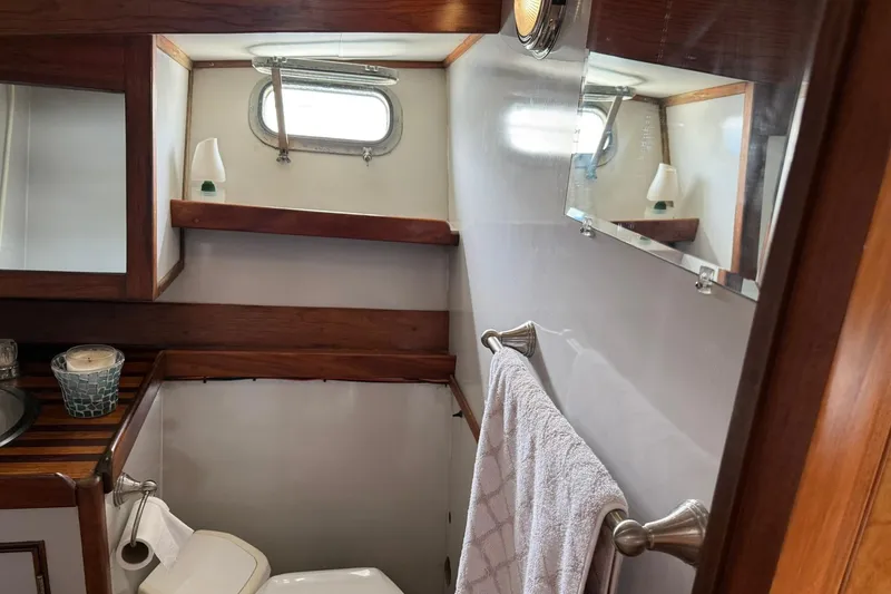 Slide: The Image of 1979 Pacific Bluefin Sportfisher bathroom with wood accents, towel rack, and porthole window. - 15