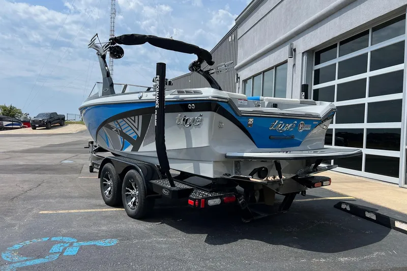 Slide: The Image of 2016 Tigé Z1 boat on trailer, parked outside a building under a clear sky. - 2