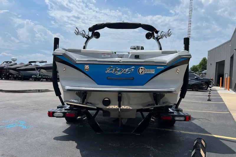 Slide: The Image of 2016 Tigé Z1 boat on trailer, parked outdoors near other boats and a building. - 3
