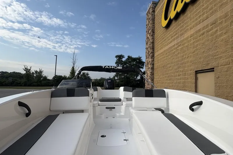 Slide: The Image of 2026 Tahoe TAHT18 boat with seating, parked near a building under a blue sky. - 1