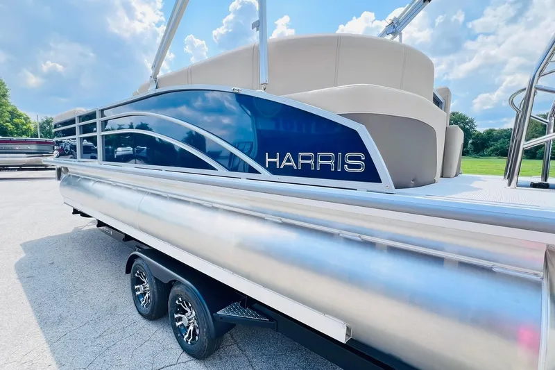 Slide: The Image of 2026 Harris Cruiser Sunliner 250 CW boat with 200HP engine, parked outdoors. - 33
