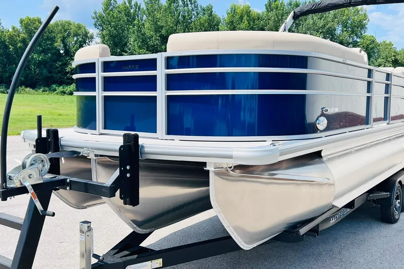 Slide: The Image of 2026 Harris Cruiser Sunliner 250 CW 200HP pontoon boat on trailer, parked outdoors. - 5