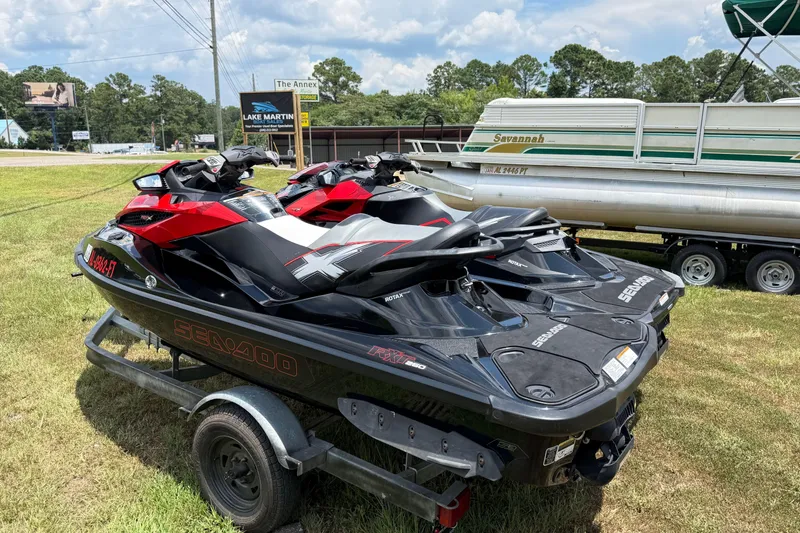 Slide: The Image of 2014 Sea-Doo RXT-X 260 jet skis on trailer, parked near a boat and sign. - 5
