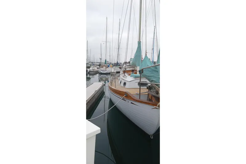 Slide: The Image of Vintage 1978 Baba Cutter sailboat docked in a marina, surrounded by other boats. - 11