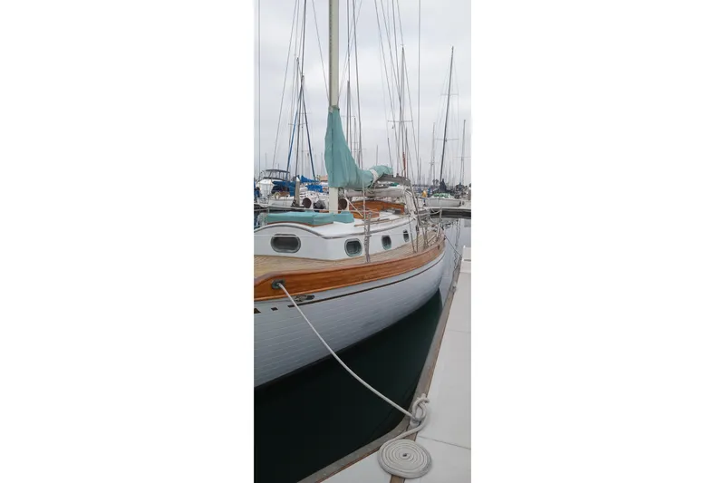 Slide: The Image of 1978 Baba Cutter sailboat docked at marina, featuring classic wooden design. - 13