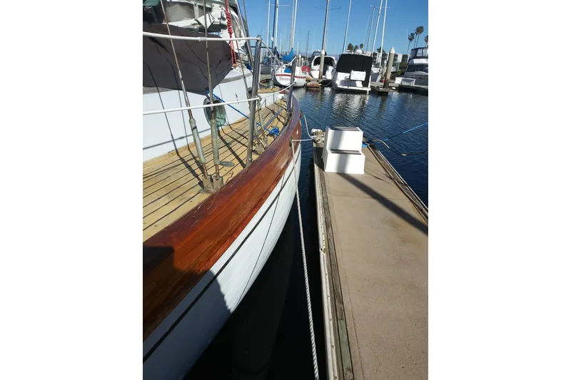 Slide: The Image of 1978 Baba Cutter sailboat docked at marina, showcasing wooden deck and railing. - 7