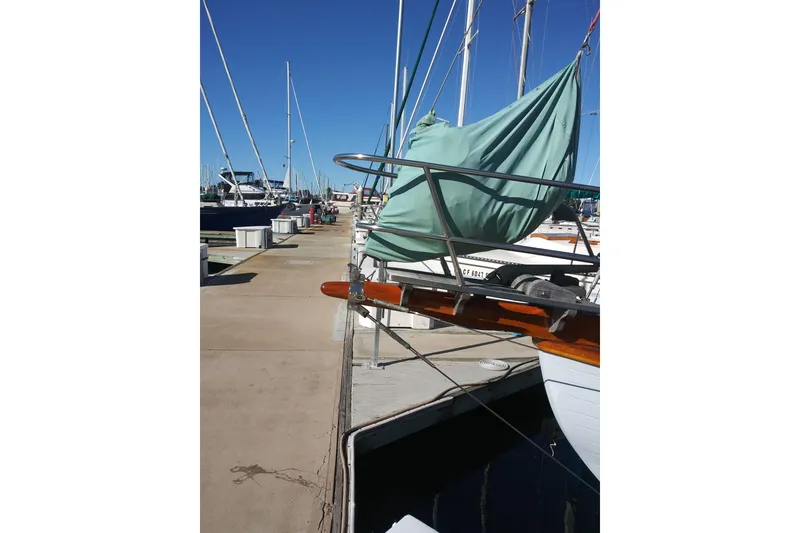 Slide: The Image of 1978 Baba Cutter sailboat docked at marina, covered with green tarp. - 8