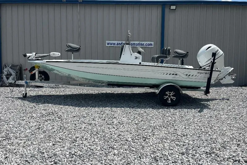 Slide: The Image of 2026 Xpress H20 BAY boat on trailer, parked on gravel, side view. - 1