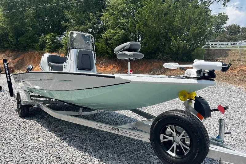 Slide: The Image of 2026 Xpress H20 BAY boat on trailer, parked on gravel, surrounded by trees. - 2