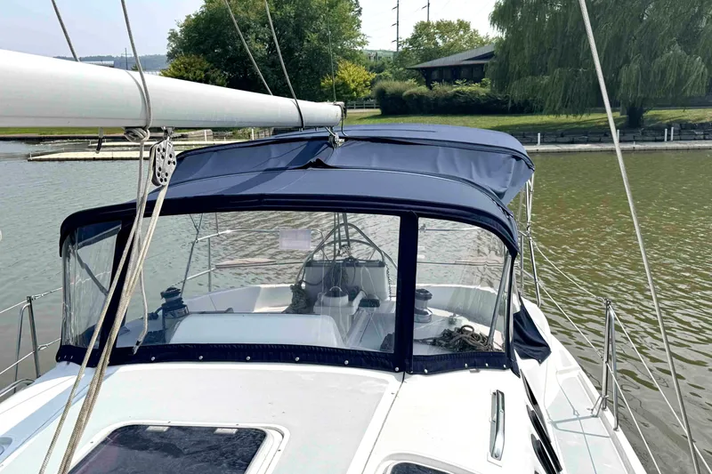 Slide: The Image of Sailboat Hunter 336, 1995 model, with blue canopy docked on a calm river. - 10