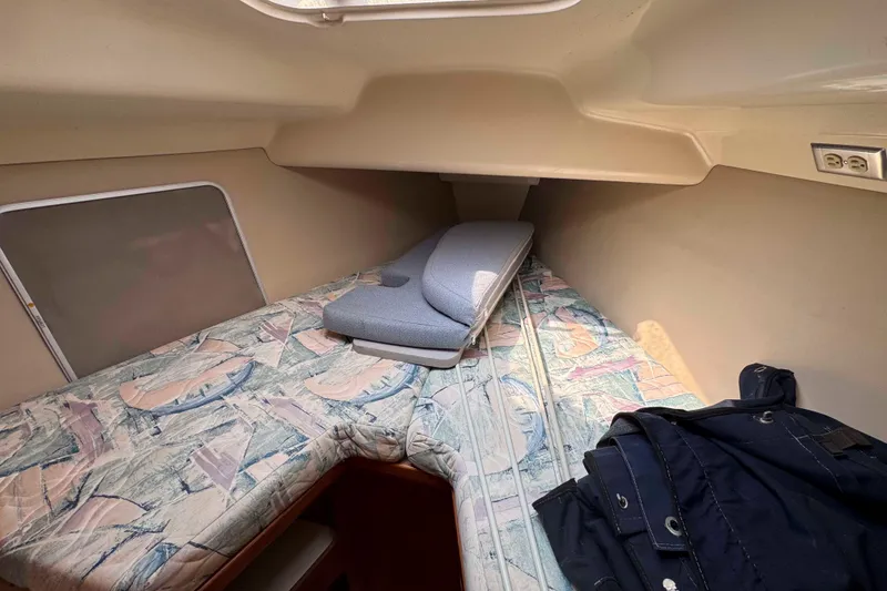 Slide: The Image of Interior cabin of a 1995 Hunter 336 sailboat with patterned bedding and a jacket. - 26