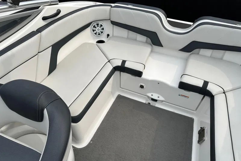 Slide: The Image of 2015 Yamaha Boats AR210 interior with white and black seating, featuring a speaker and cup holder. - 2