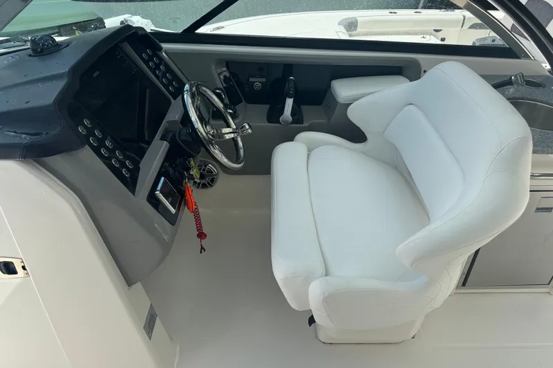 Slide: The Image of 2021 Robalo R317 Dual Console helm with white captain's chair and modern dashboard controls. - 16
