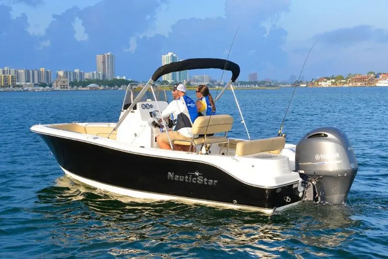 Slide: The Image of Manufacturer Provided Image: 2020 NauticStar 20 XS Offshore boat cruising on water with city skyline in background. - 13