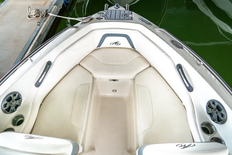 Slide: The Image of 2013 Monterey 204FS boat interior with cushioned seating and cup holders, docked on green water. - 15