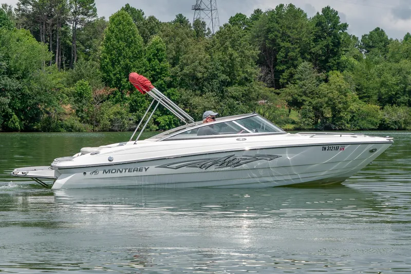 Slide: The Image of 2013 Monterey 204FS boat cruising on a serene lake with lush green trees. - 4