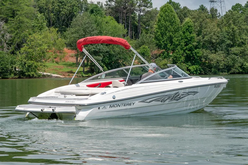 Slide: The Image of 2013 Monterey 204FS boat cruising on a serene lake with lush green surroundings. - 5